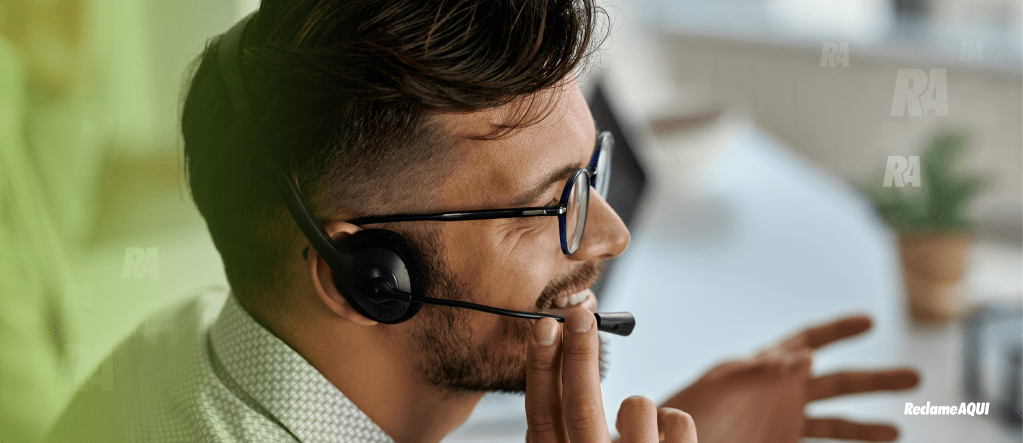 Imagem de um homem branco de barba e óculos, com um fone e microfone fazendo um atendimento