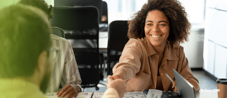 mulher sorrindo e apertando mão do cliente