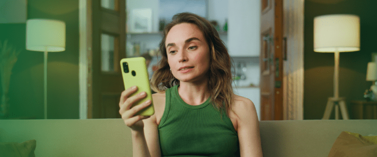 Mulher segurando celular com expressão de atenção, representando o planejamento financeiro e o pagamento de contas pelo aplicativo no início de 2026.